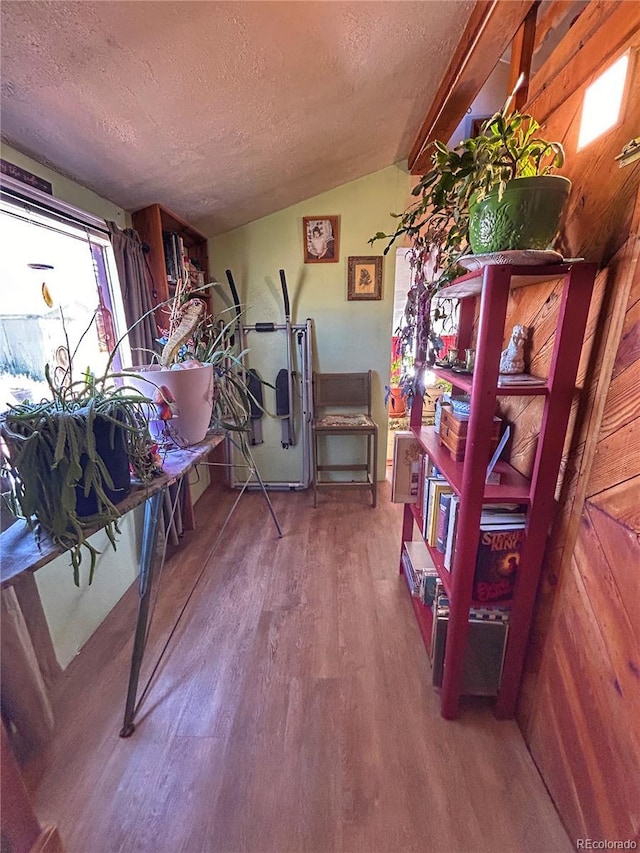 misc room with vaulted ceiling, wood finished floors, and a textured ceiling