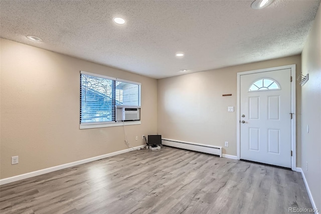 foyer entrance with a textured ceiling, a baseboard radiator, cooling unit, and light hardwood / wood-style floors