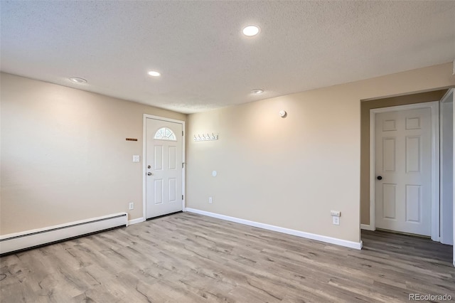 entryway featuring a textured ceiling, light wood-type flooring, and a baseboard heating unit