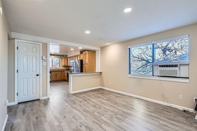 unfurnished living room with cooling unit and light hardwood / wood-style floors