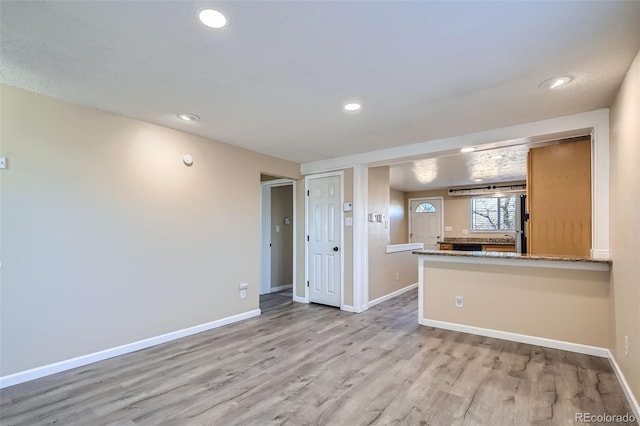 kitchen with light stone countertops, kitchen peninsula, and light hardwood / wood-style flooring