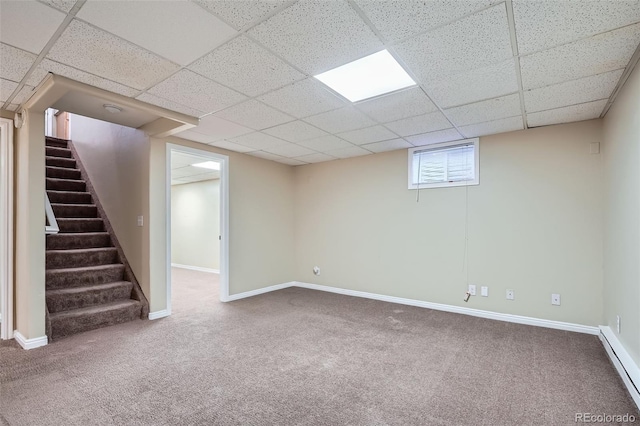 basement with a paneled ceiling, carpet, and a baseboard radiator