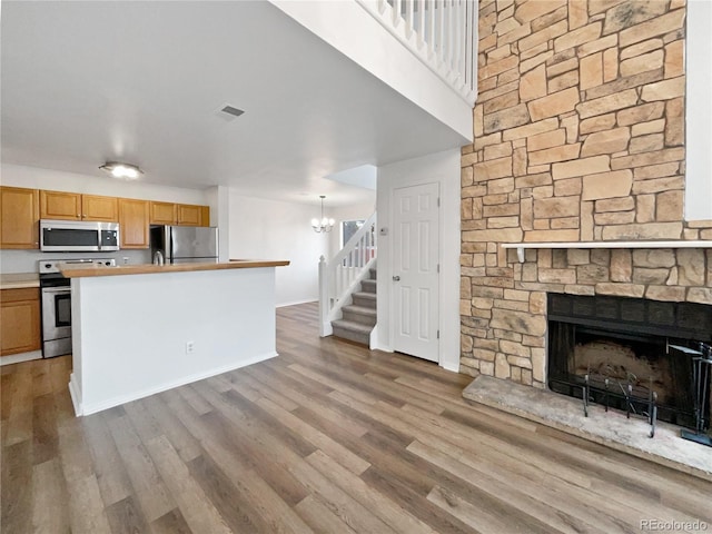 5550 W 80th Pl Unit 20, Arvada, CO 80003 - kitchen with stainless steel appliances, a fireplace, wood finished floors, light countertops, and a chandelier