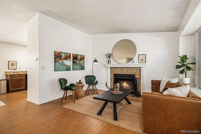 sitting room with a tiled fireplace, light hardwood / wood-style floors, and a textured ceiling