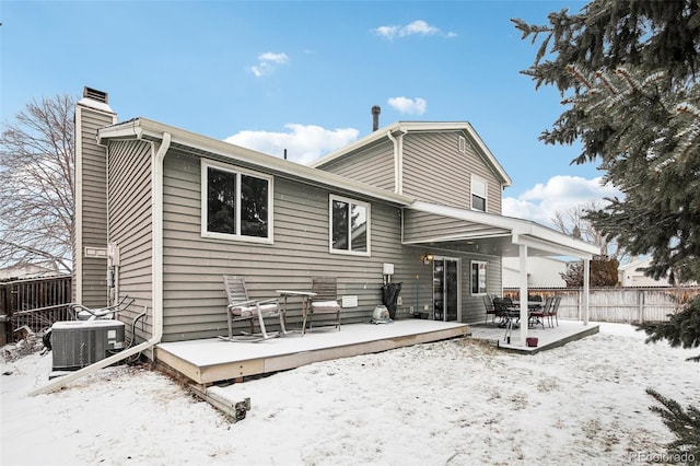 snow covered rear of property with cooling unit and a deck