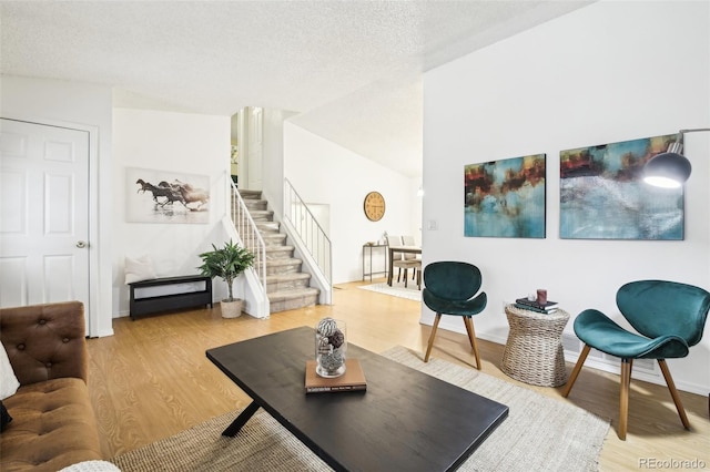 living room with hardwood / wood-style flooring, vaulted ceiling, and a textured ceiling