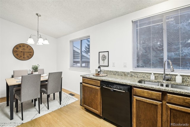 kitchen with lofted ceiling, sink, dishwasher, pendant lighting, and light hardwood / wood-style floors