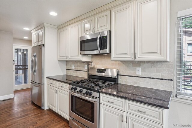 7650 W 24th Ave, Lakewood, CO 80214 - kitchen featuring stainless steel appliances, backsplash, dark wood-type flooring, dark stone counters, and recessed lighting