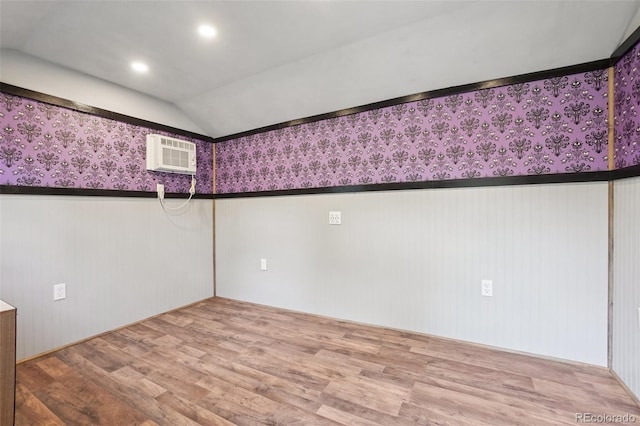 7650 W 24th Ave, Lakewood, CO 80214 - empty room featuring wood finished floors, vaulted ceiling, a wainscoted wall, wallpapered walls, and a wall mounted AC
