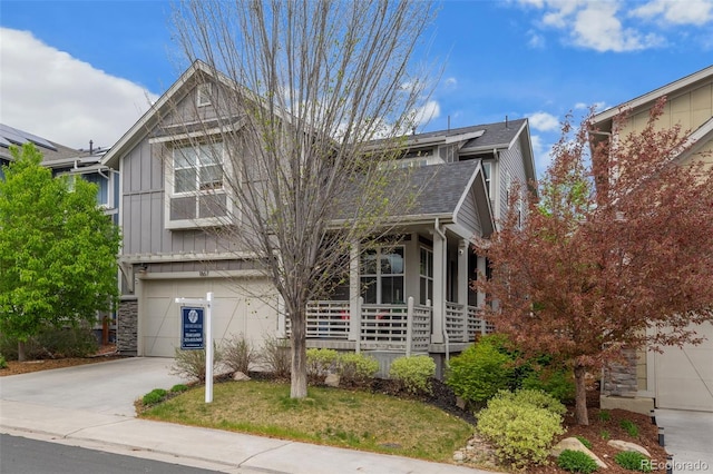 view of front facade with board and batten siding, a porch, driveway, a garage, and stone siding
