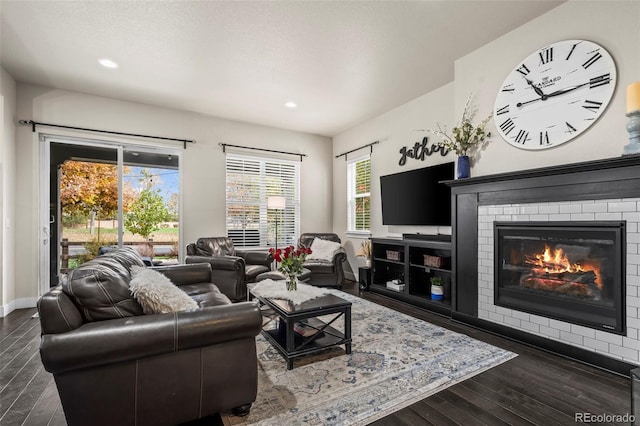 living area with recessed lighting, baseboards, a brick fireplace, and dark wood-style floors
