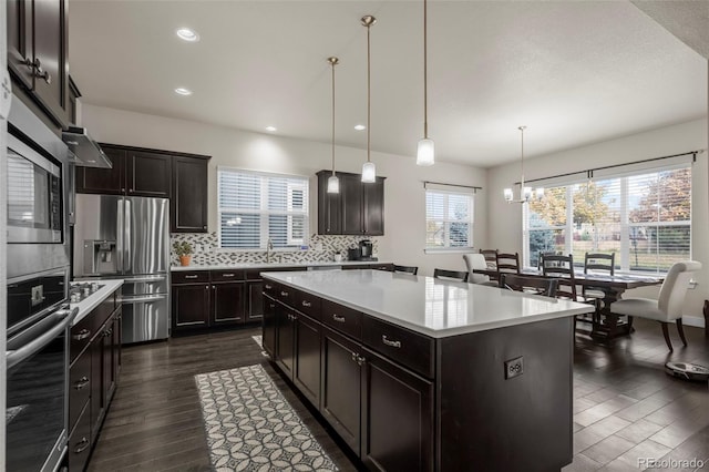 kitchen featuring light countertops, appliances with stainless steel finishes, backsplash, and dark wood finished floors