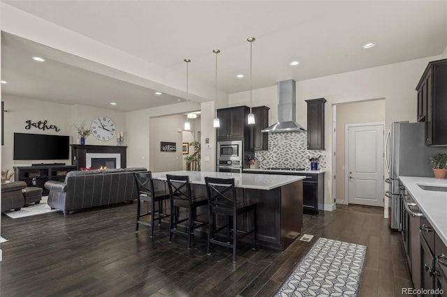 kitchen with light countertops, open floor plan, wall chimney range hood, and stainless steel appliances