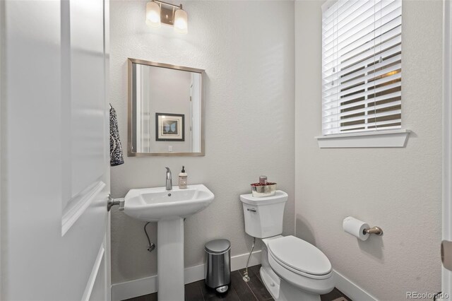 half bath featuring baseboards and toilet