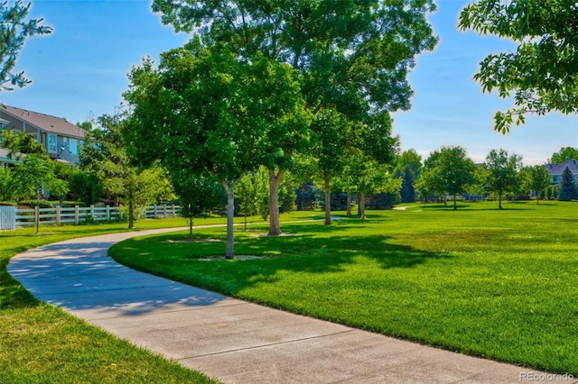 view of property's community with a lawn and fence