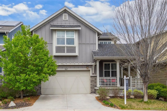 craftsman house with board and batten siding, concrete driveway, an attached garage, a shingled roof, and stone siding