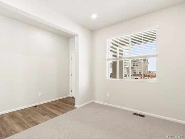 unfurnished room featuring carpet floors, visible vents, and baseboards