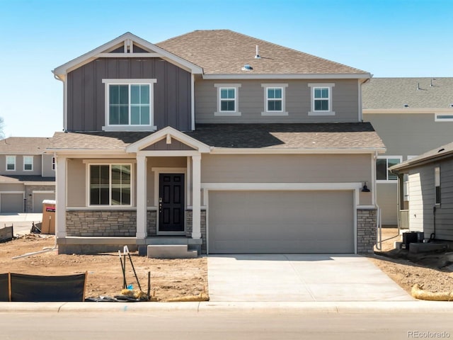 view of front of property with stone siding, roof with shingles, board and batten siding, concrete driveway, and a garage