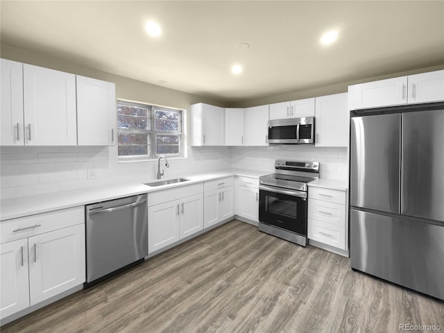 kitchen with white cabinets, backsplash, sink, and stainless steel appliances