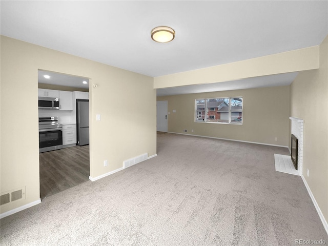 unfurnished living room featuring carpet flooring and a fireplace