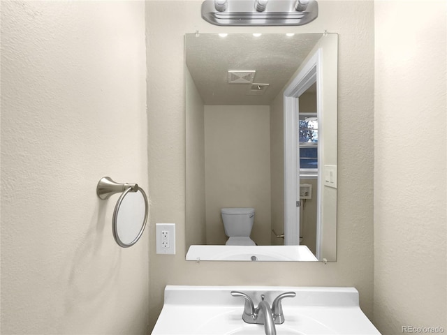 bathroom featuring sink, a textured ceiling, and toilet