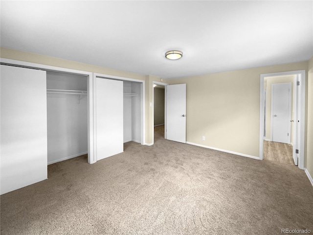 unfurnished bedroom with multiple closets and carpet