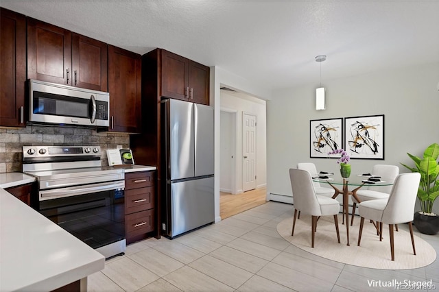 kitchen featuring a baseboard heating unit, backsplash, pendant lighting, light tile patterned floors, and appliances with stainless steel finishes