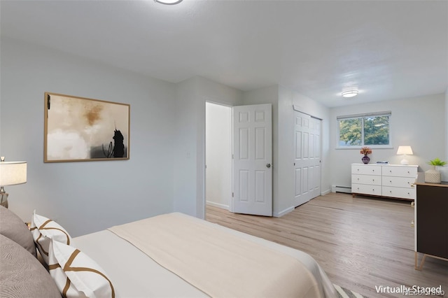 bedroom featuring a baseboard radiator, wood-type flooring, and a closet