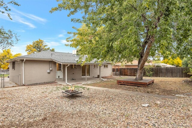 8467 W 62nd Pl, Arvada, CO 80004 - rear view of property with a deck, a patio, a fenced backyard, brick siding, and an outdoor fire pit