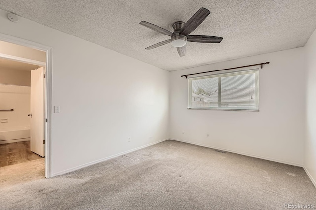 carpeted empty room with a ceiling fan, a textured ceiling, baseboards, and a smoke detector