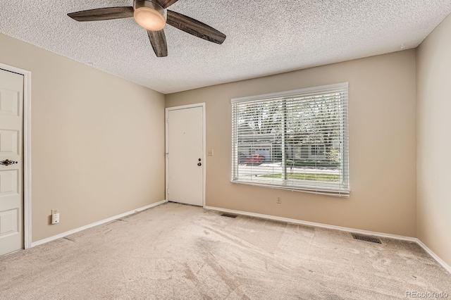carpeted spare room featuring a ceiling fan, a textured ceiling, and baseboards