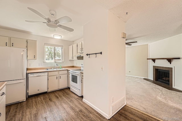 kitchen featuring white appliances, a ceiling fan, wood finished floors, a sink, and light countertops