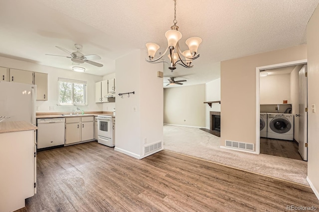 kitchen with white appliances, ceiling fan, washer and clothes dryer, light countertops, and a chandelier