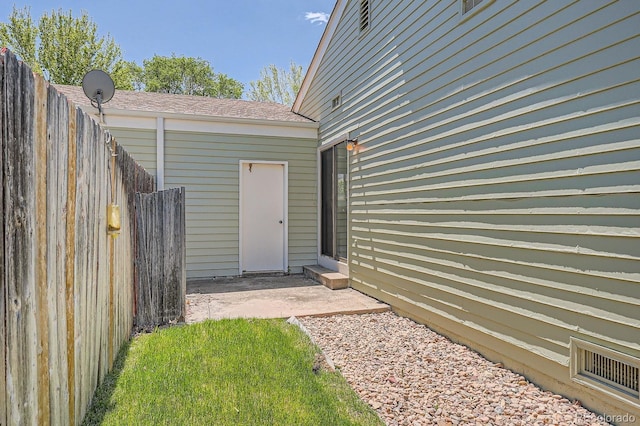 doorway to property with fence, a patio, and a shingled roof