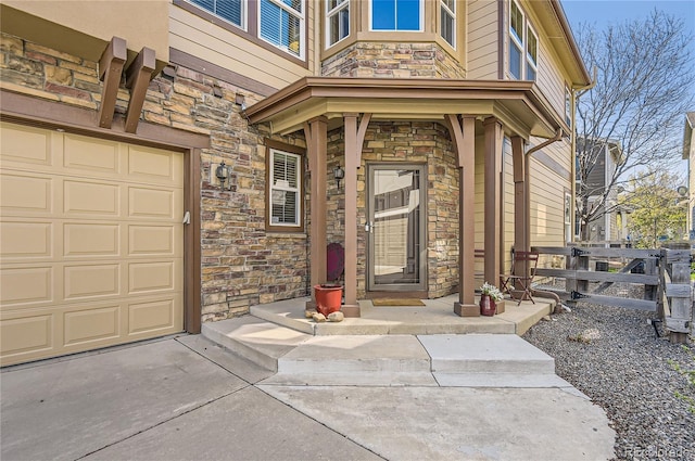 entrance to property with fence, stone siding, driveway, and a garage