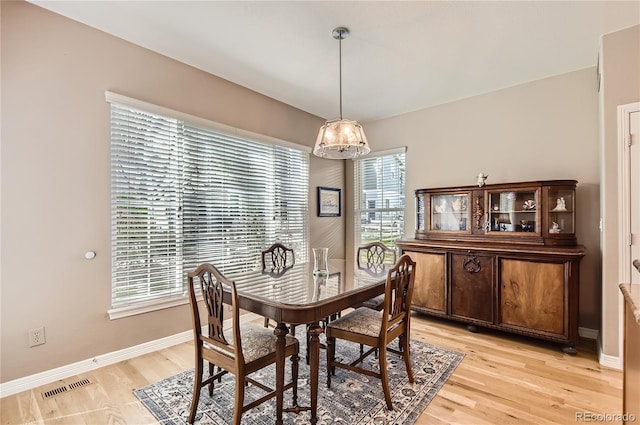 dining room featuring baseboards, light wood-style flooring, visible vents, and an inviting chandelier