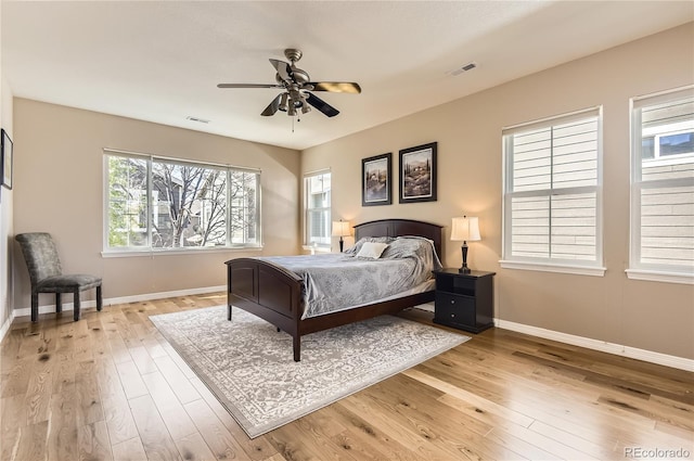 bedroom featuring visible vents, light wood finished floors, baseboards, and ceiling fan