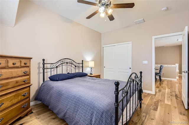 bedroom with light wood-type flooring, a ceiling fan, baseboards, and a closet