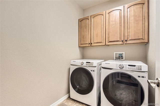 washroom with washing machine and clothes dryer, cabinet space, and baseboards
