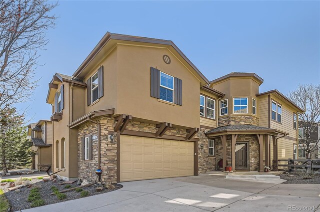 townhome / multi-family property featuring an attached garage, stone siding, and stucco siding