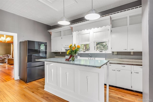 kitchen with light hardwood / wood-style flooring, decorative light fixtures, black refrigerator, and white cabinetry