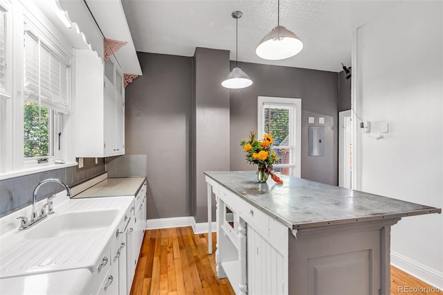 kitchen featuring hanging light fixtures, light hardwood / wood-style floors, white cabinetry, and a center island