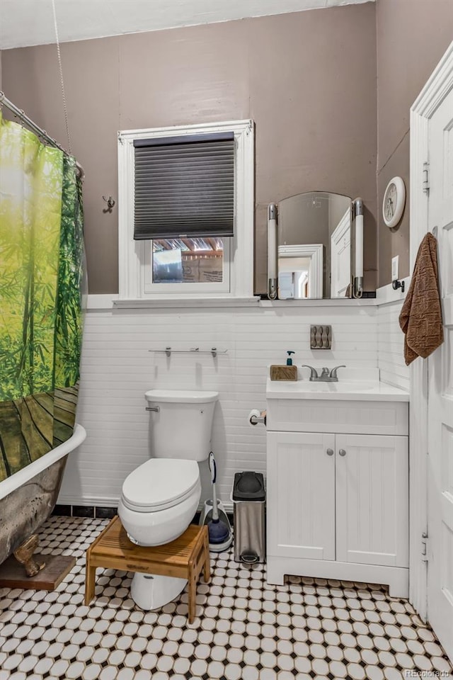 bathroom featuring tile walls, curtained shower, vanity, and toilet