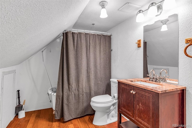 bathroom featuring hardwood / wood-style flooring, vaulted ceiling, a shower with curtain, vanity, and toilet