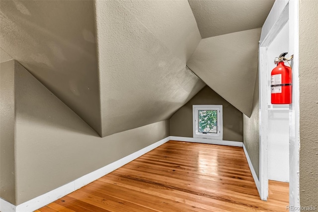 bonus room featuring lofted ceiling, a textured ceiling, and hardwood / wood-style floors