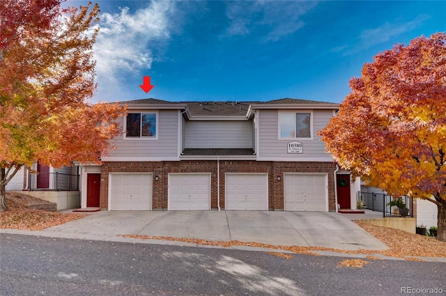 view of front of house featuring driveway, brick siding, fence, an attached garage, and a shingled roof