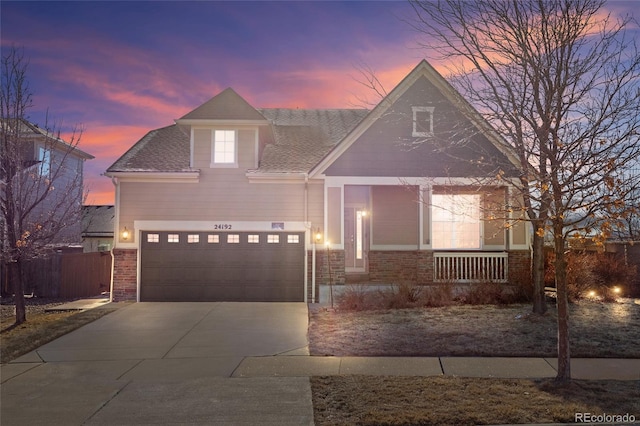 view of front of property with covered porch, a shingled roof, brick siding, fence, and concrete driveway