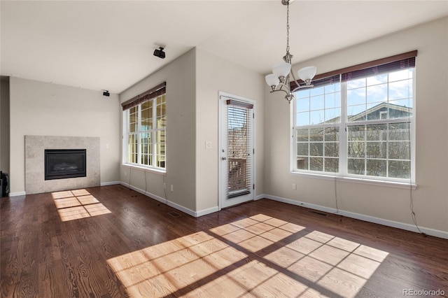 unfurnished dining area with a chandelier, a fireplace, baseboards, and wood finished floors