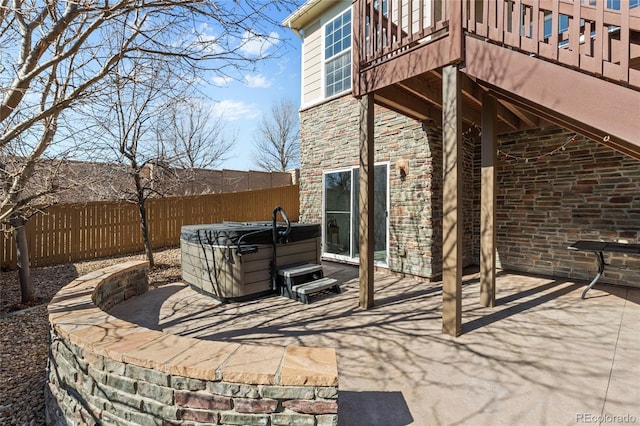 view of patio with a balcony, a hot tub, and fence