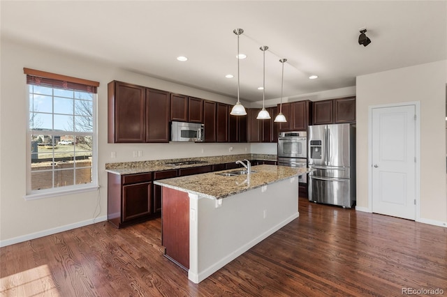 kitchen with light stone counters, appliances with stainless steel finishes, dark wood-type flooring, dark brown cabinets, and a sink